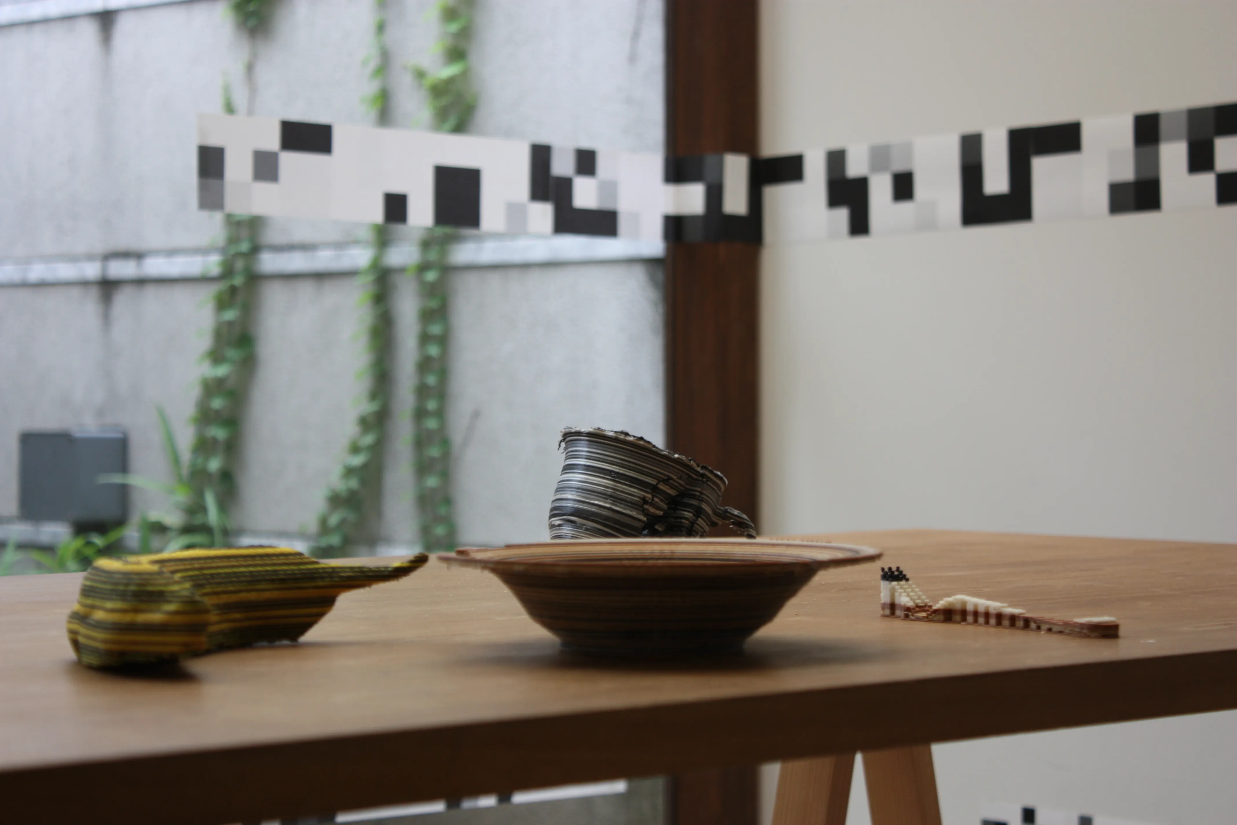 Sculpted banana, plate, and fork on a wooden table beneath black-and-white wall markings